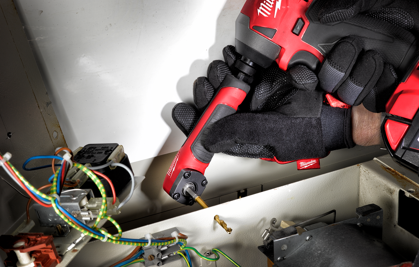 Hand wearing black gloves using Milwaukee SHOCKWAVE™  Impact Right Angle Adapter on electrical wiring in home improvement setting