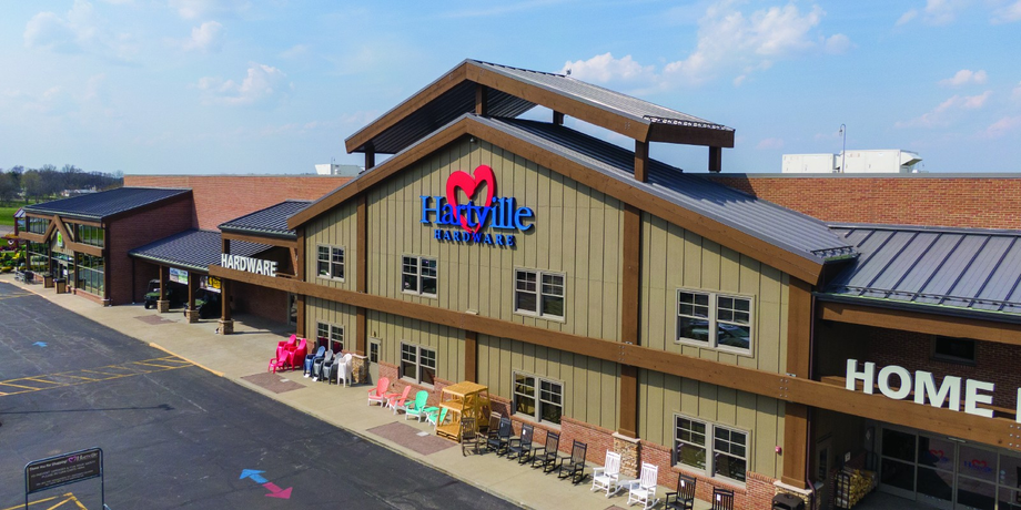 Exterior view of a large rustic-style hardware store with Hartville Hardware logo featuring a red heart above the entrance and colorful chairs displayed outside.