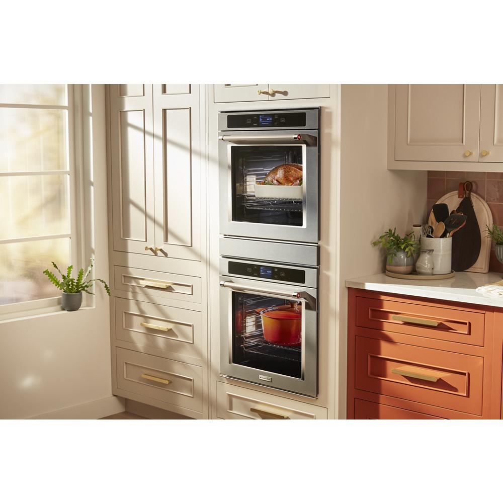 KitchenAid stainless steel smart double wall oven with food inside, fitted in beige and rust-colored kitchen cabinetry