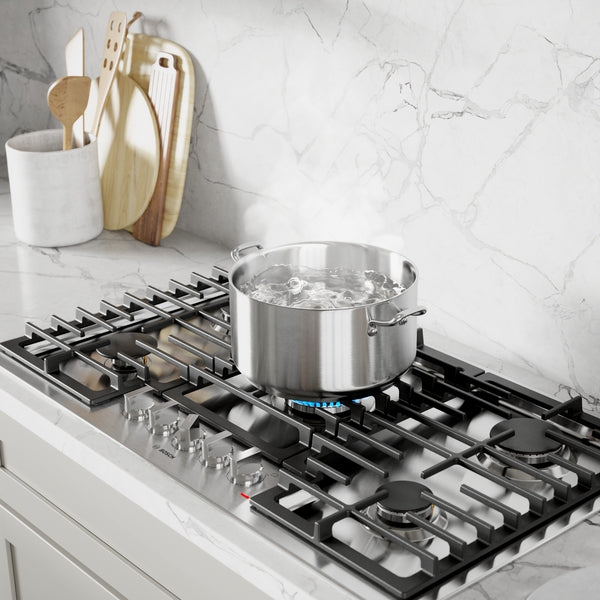 Stainless steel 36-inch gas cooktop with five burners and simmering pot on marble countertop in modern kitchenware collection