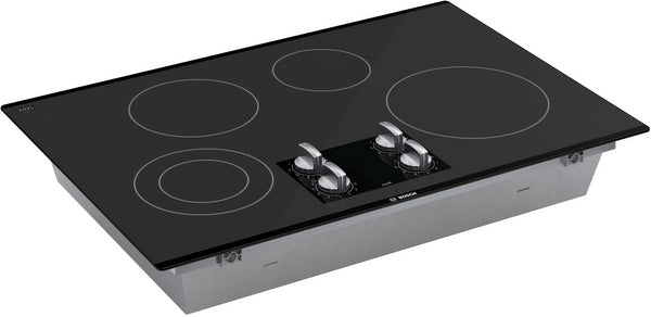 Black seamless glass electric cooktop with four burners and dual control knobs in kitchen appliances collection