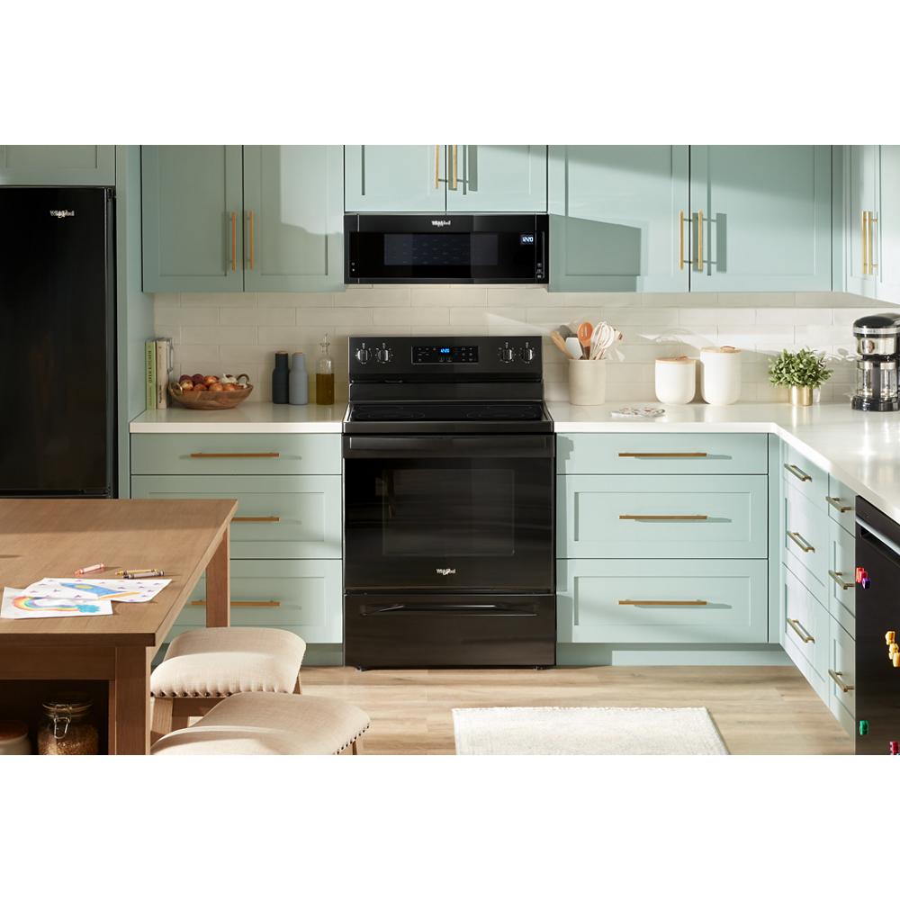 Black 30-inch electric range with sleek digital display and control knobs, set in a modern kitchen with mint cabinetry and wood flooring