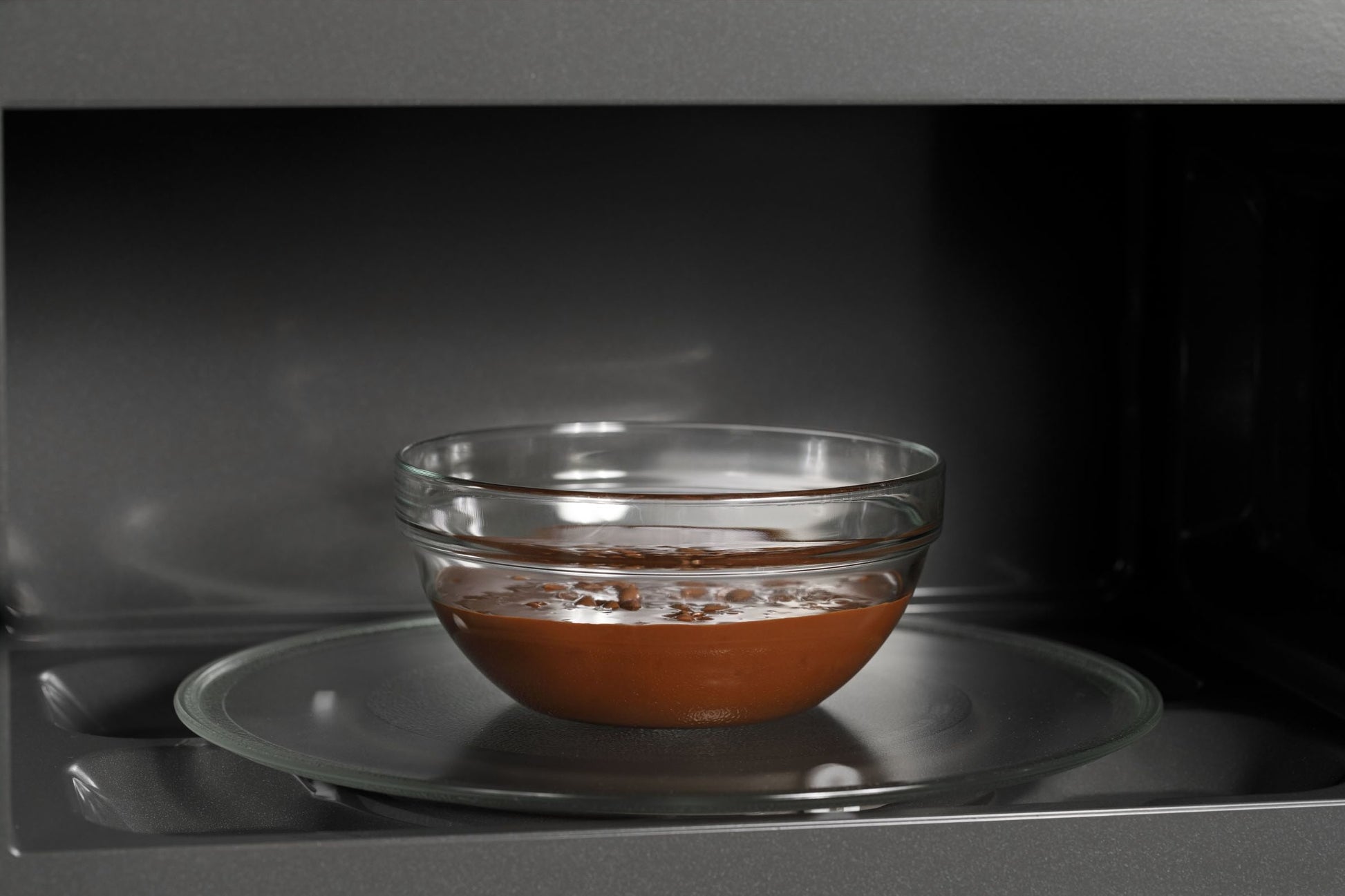 Glass bowl with chocolate mixture inside a microwave oven interior from kitchen appliances collection