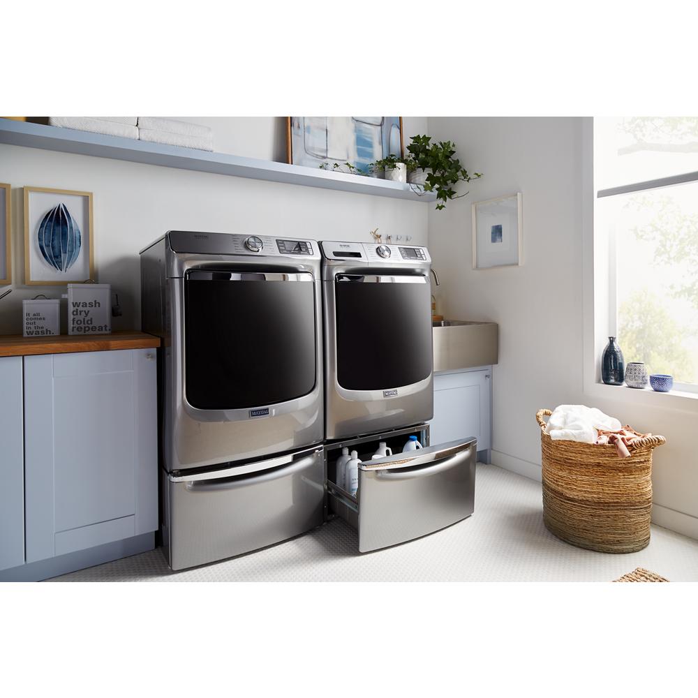 Modern laundry room with stainless steel washer and dryer on storage pedestals holding detergent and supplies inside drawer