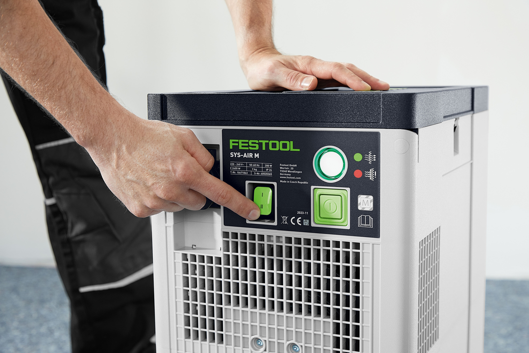 Person pressing power button on Festool SYS-AIR M air filter for dust management in woodworking tools collection