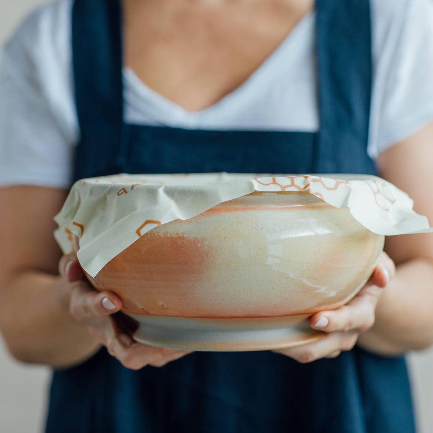 Person holding ceramic bowl covered with beeswax honeycomb-patterned wrap for kitchen storage under $50