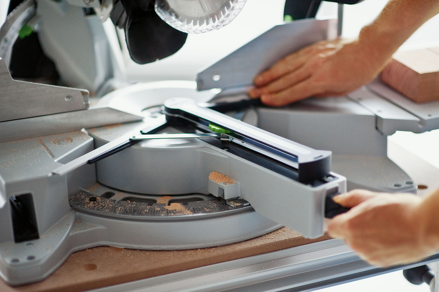 Person adjusting sliding compound miter saw for accurate cuts in home improvement and power tools collection
