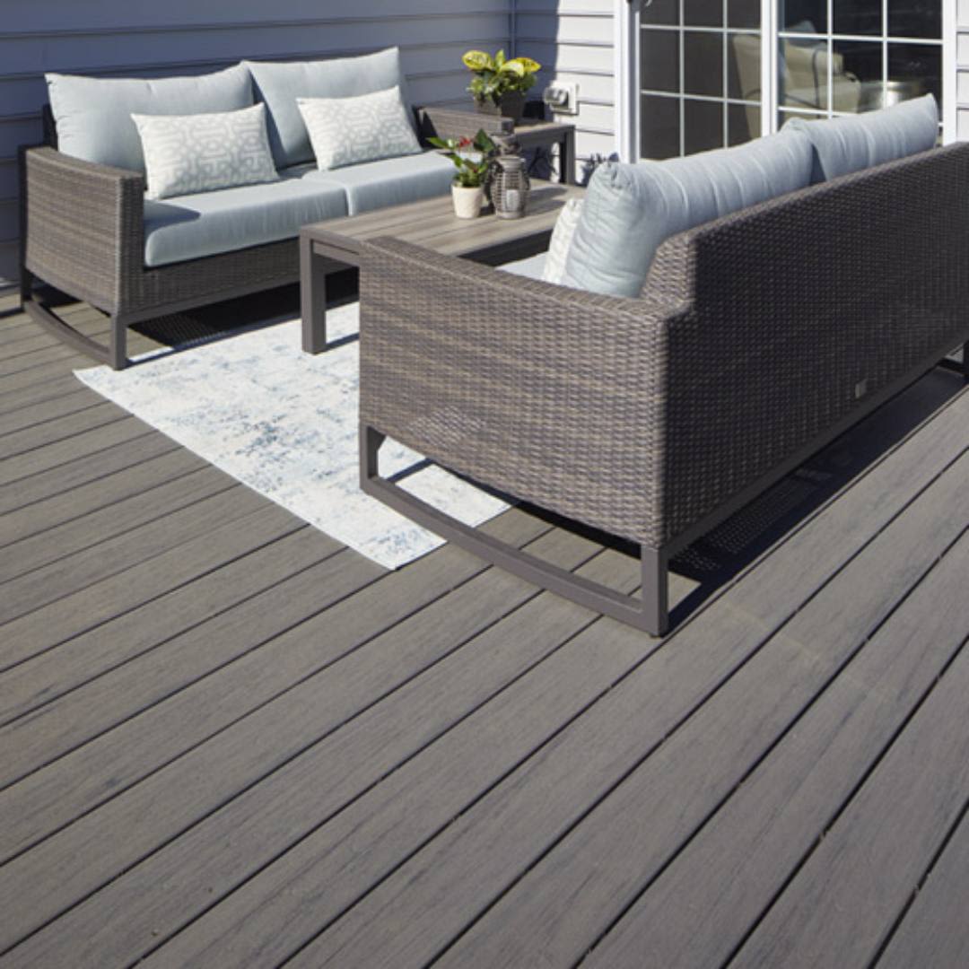 Outdoor seating area with wicker sofas and light cushions on a gray composite deck in home improvement setting