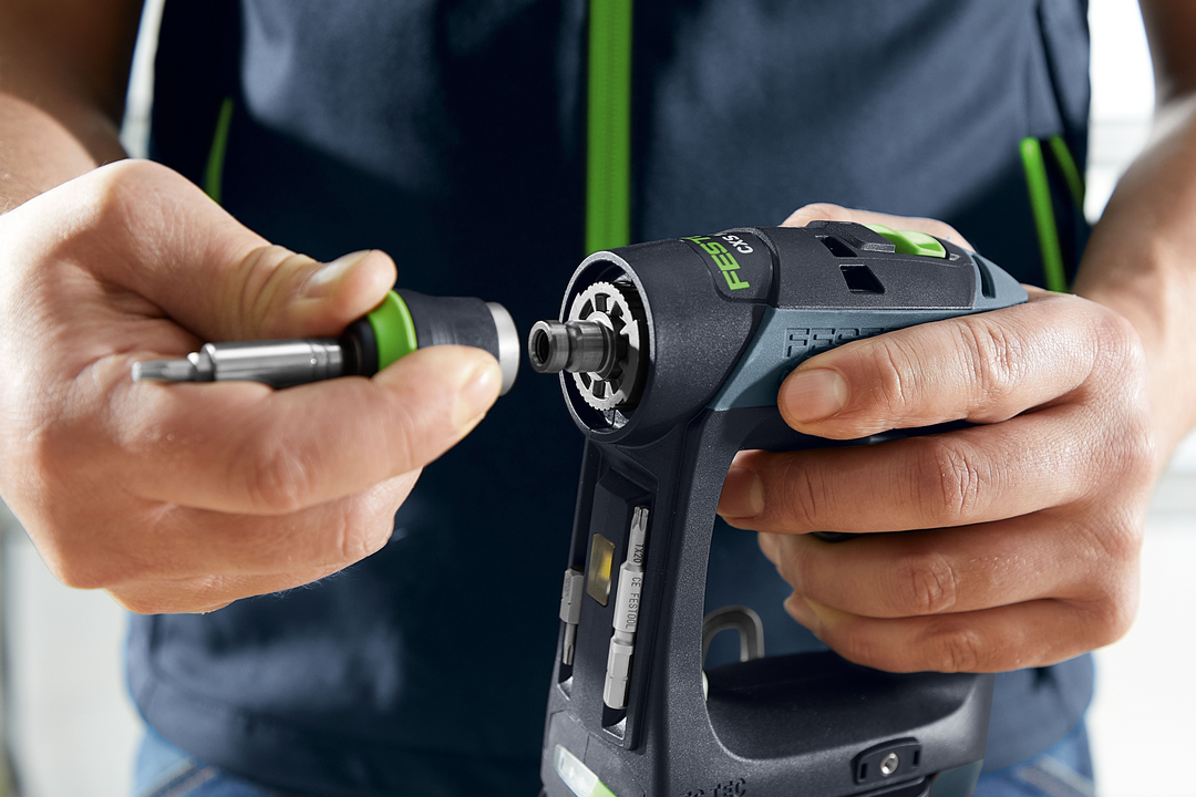 Hands attaching a screwdriver bit to a compact Festool cordless drill designed for woodworking power tools