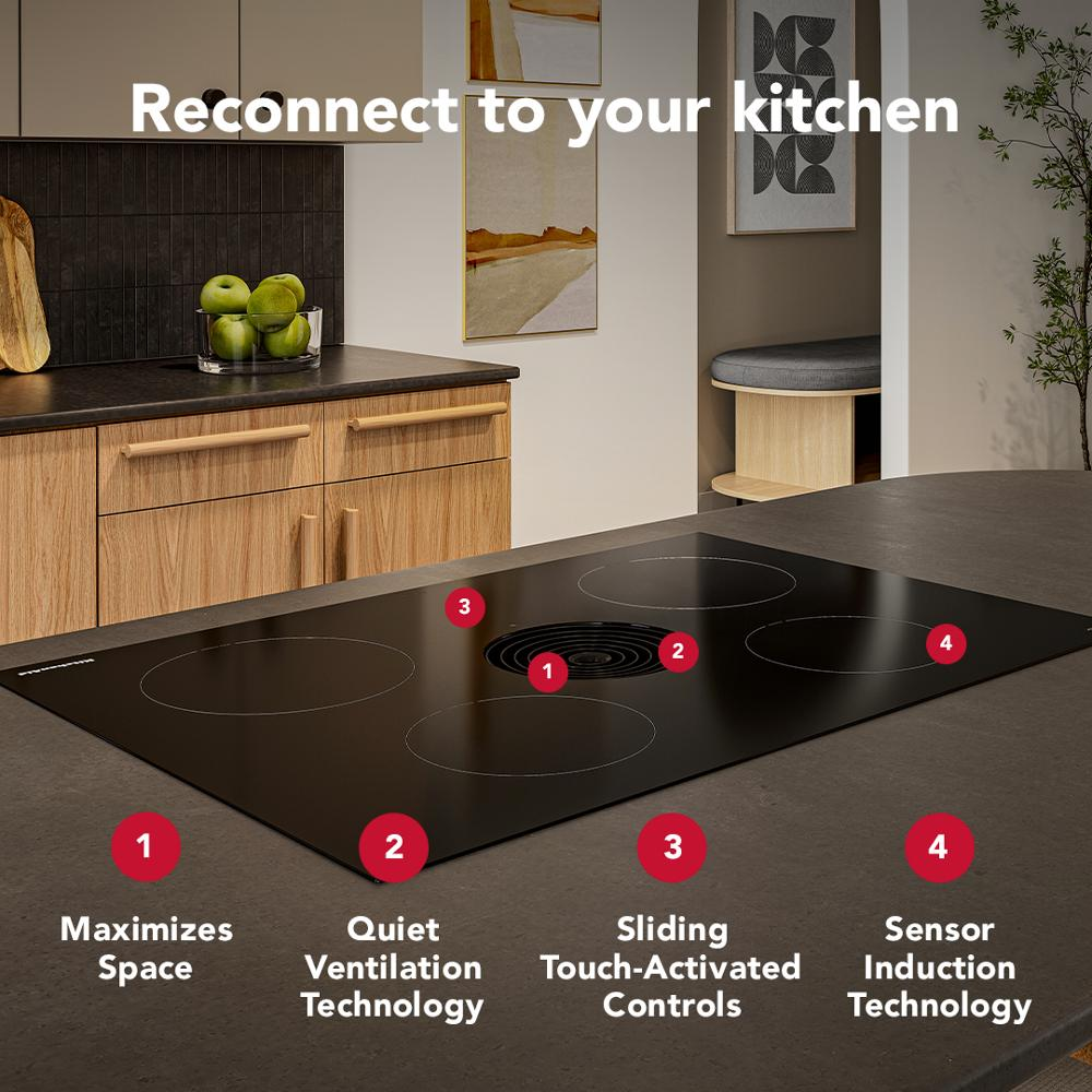 Black induction cooktop with four cooking zones and central downdraft vent showcasing touch controls in modern kitchen setting