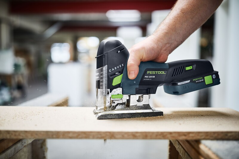 Hand operating Festool cordless jigsaw cutting wood panel during a home improvement project