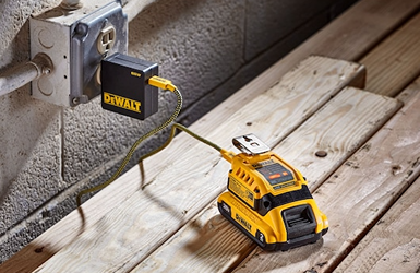 Yellow DEWALT 20V MAX USB charger connected to wall outlet and charging battery on wooden surface in tool accessories