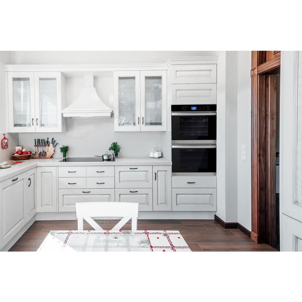 Built-in double wall oven with digital display in bright kitchen featuring white cabinetry and wooden flooring