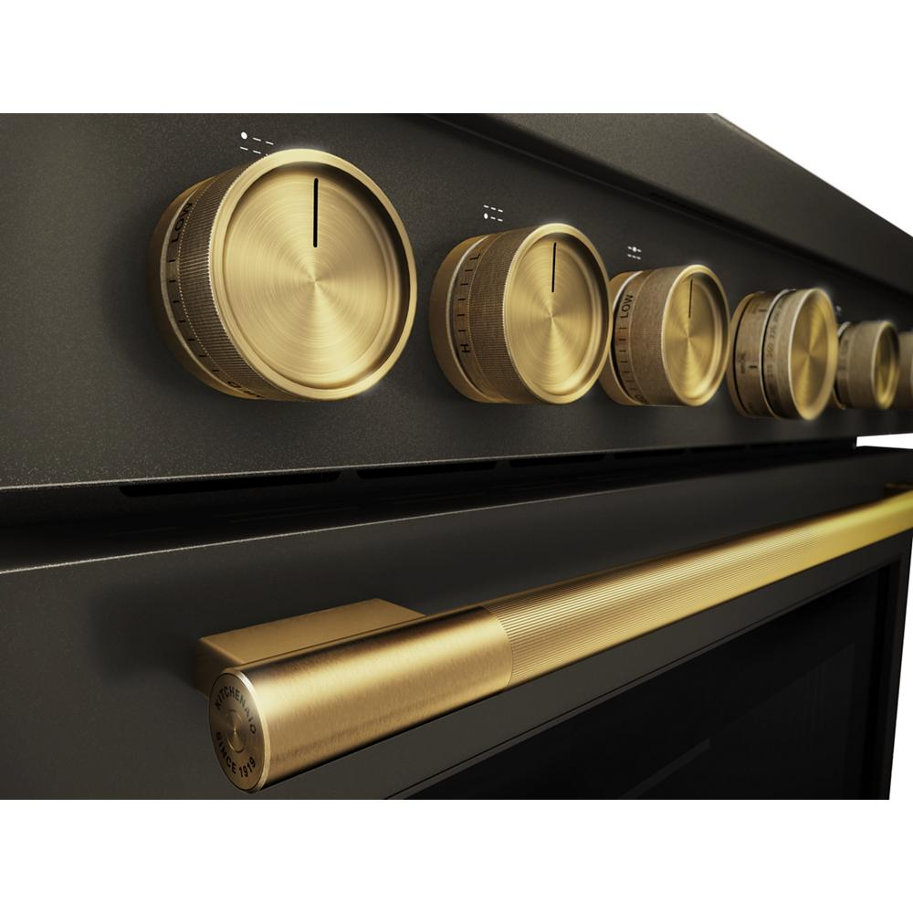 Close-up of brushed brass control knobs and matching handle on black commercial-style dual fuel range from KitchenAid collection
