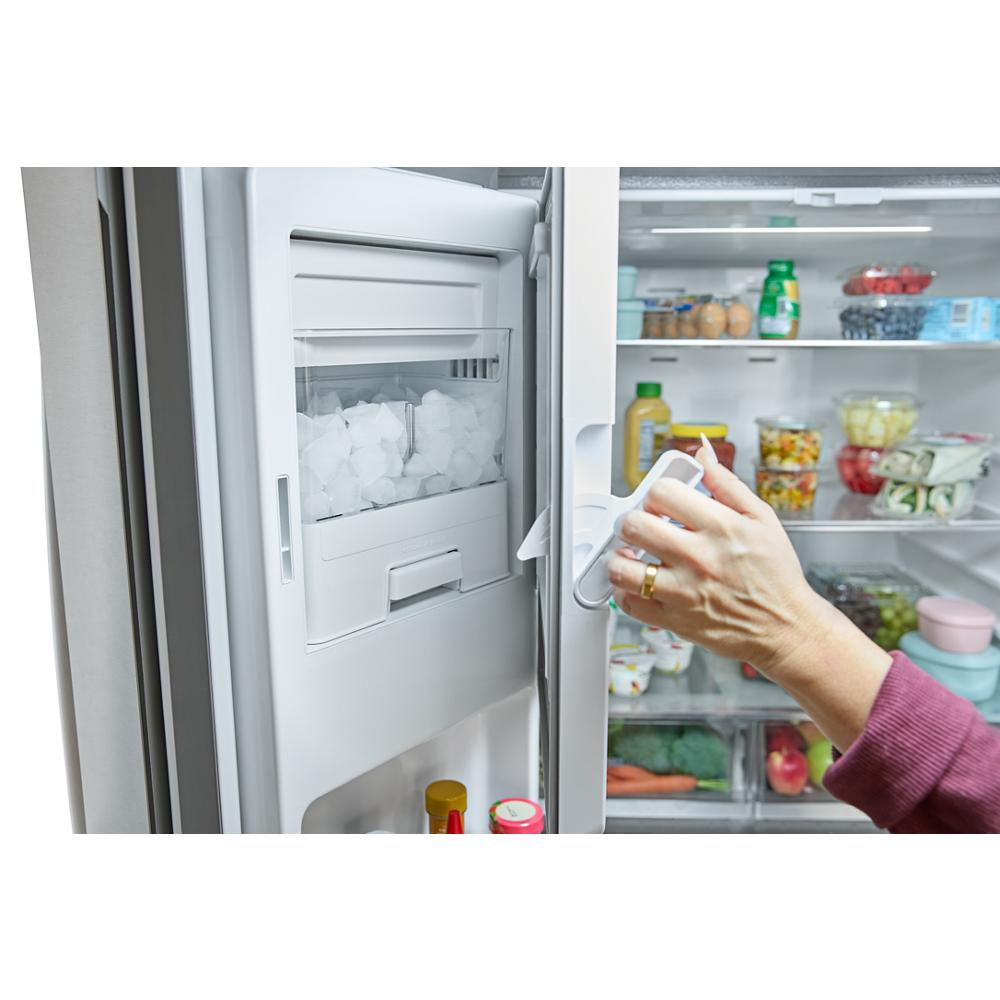 Hand opening stainless steel French door refrigerator with visible in-door ice maker and well-stocked interior shelves