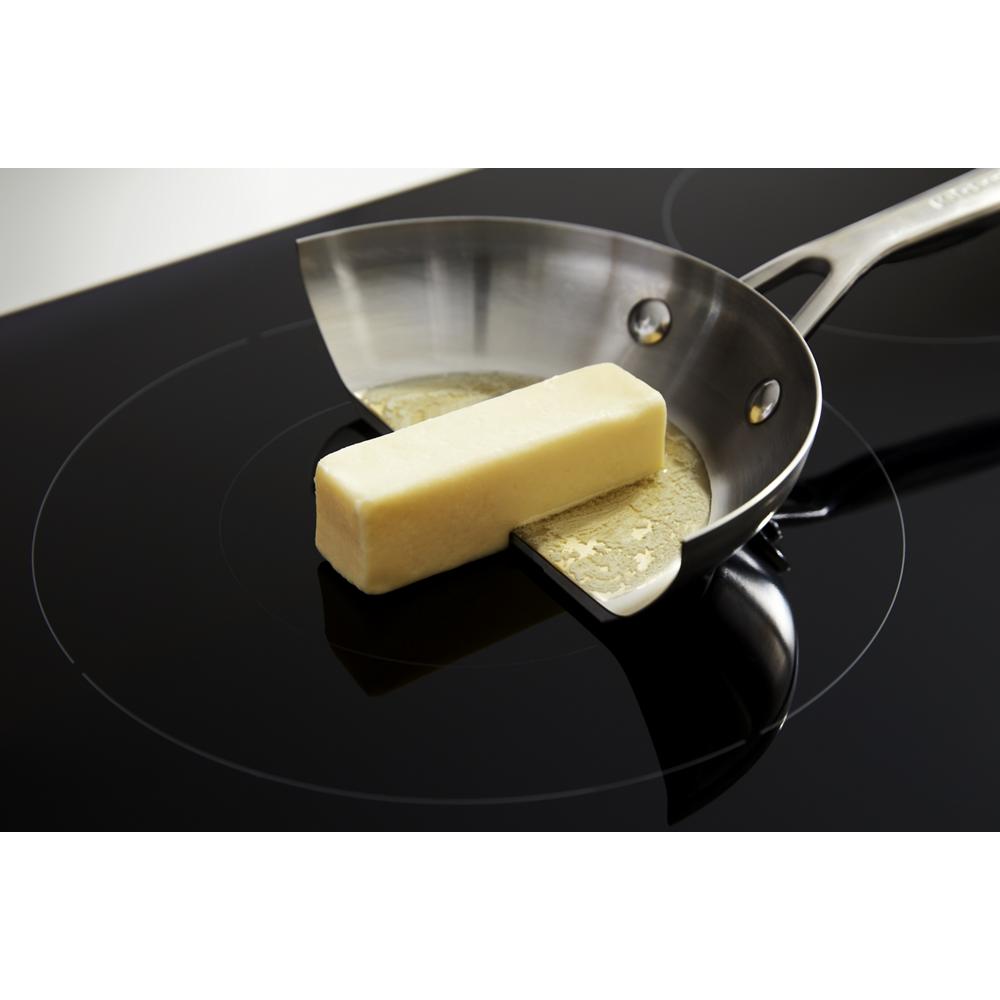 Stainless steel pan melting butter on a sleek black 36-inch sensor induction cooktop surface