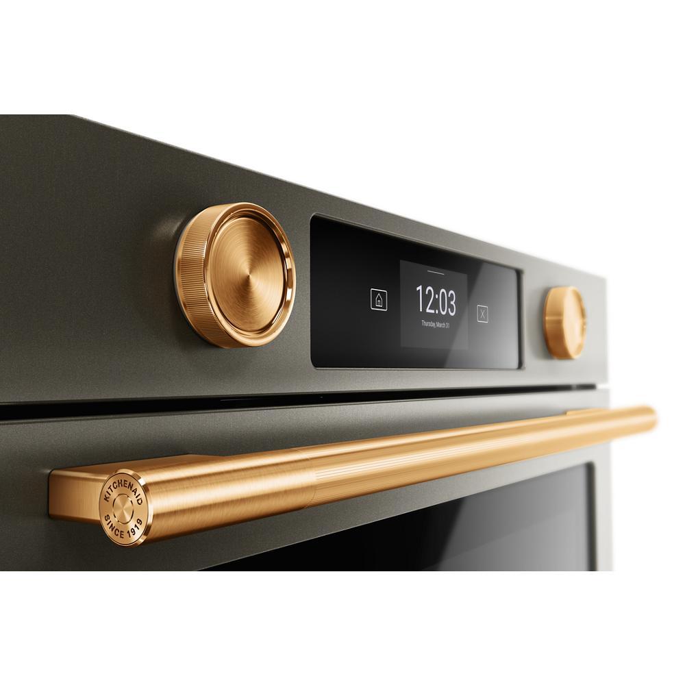 Close-up of black ore wall oven control panel with gold backlit knobs and gold handle in KitchenAid appliances collection