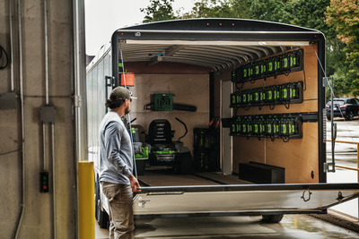 Man loading trailer with multiple black and green commercial charging hubs and power tools for home improvement use
