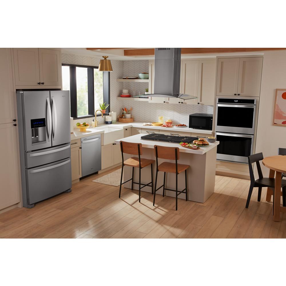 Contemporary kitchen featuring a stainless steel fridge, built-in ovens, dishwasher, and curved glass island range hood from Island Range Hoods collection