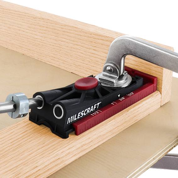 Compact black and red pocket hole jig clamped to wood with drill guide for woodworking tool accessories and home improvement