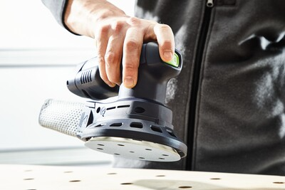 Person using a Festool cordless eccentric sander with dust extraction for precision home improvement tasks