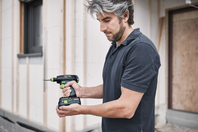 Man operating a compact cordless lithium-ion drill for home improvement and precision tasks outdoors