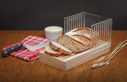 Wood base slicing guide with clear adjustable slots holding sliced bread on wooden table in kitchenware collection
