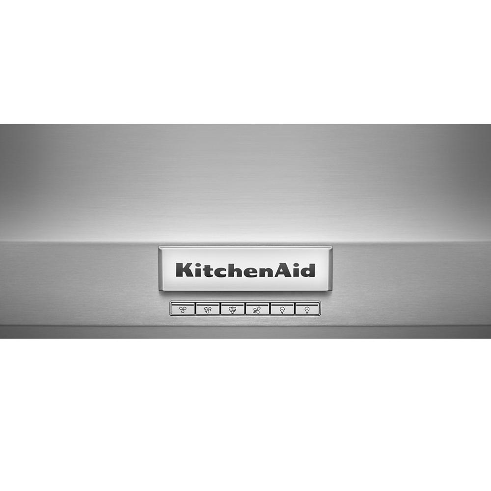 Close-up of stainless steel range hood control panel with illuminated KitchenAid logo and button icons in appliances setting