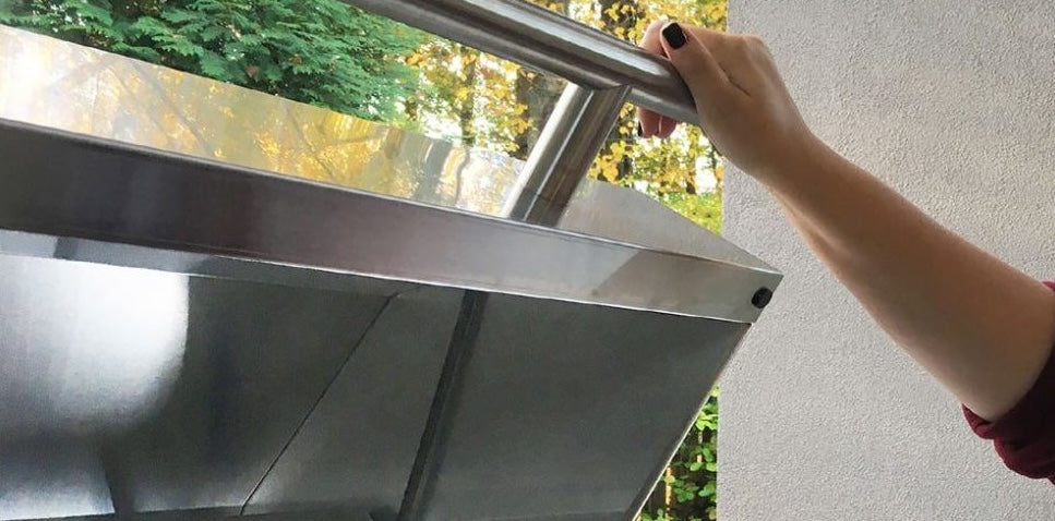 Modern stainless steel kitchen canopy hood with LED lighting being opened by a hand for home improvement use