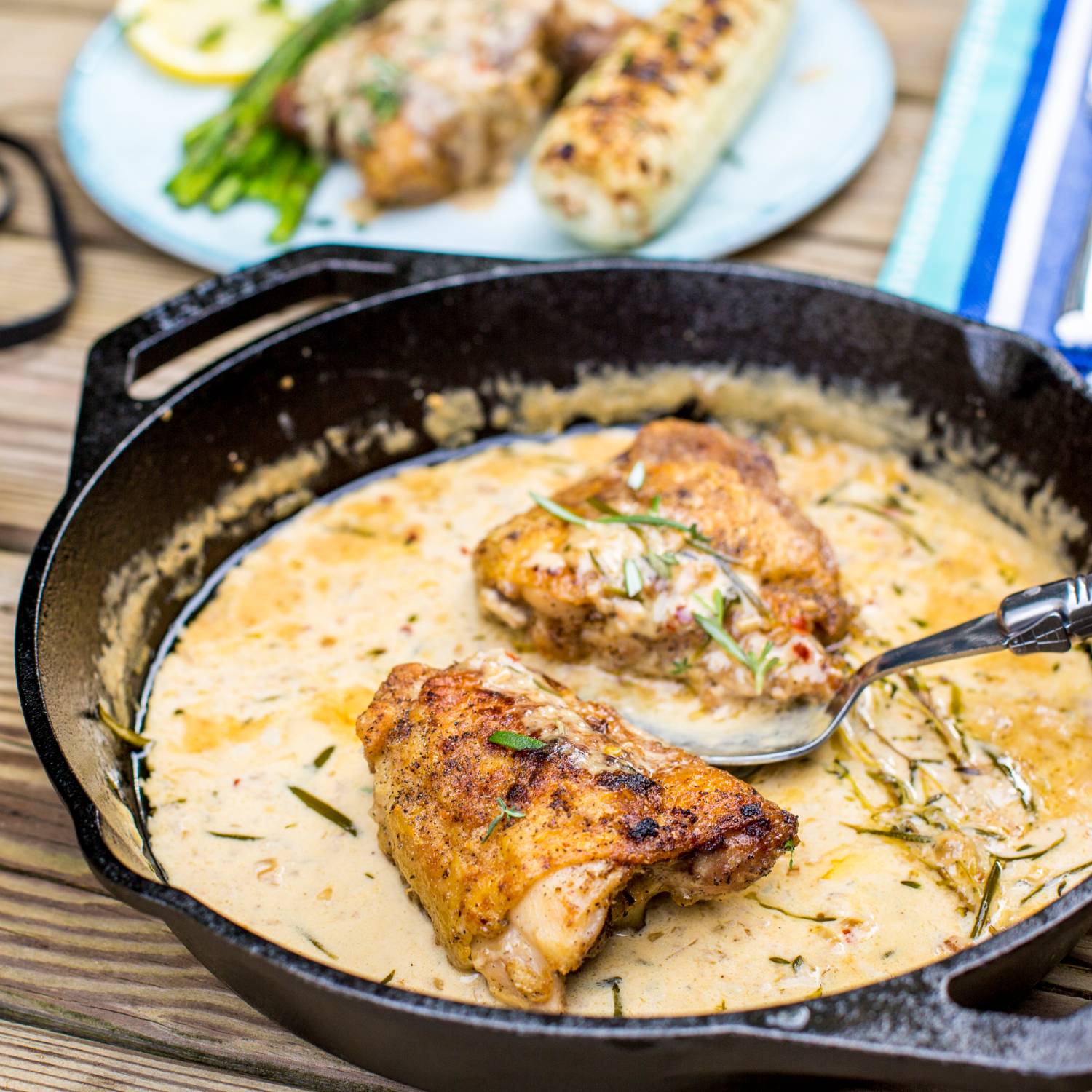 Round cast iron pan cooking creamy herb chicken with grilled corn and asparagus in kitchenware collection under $50
