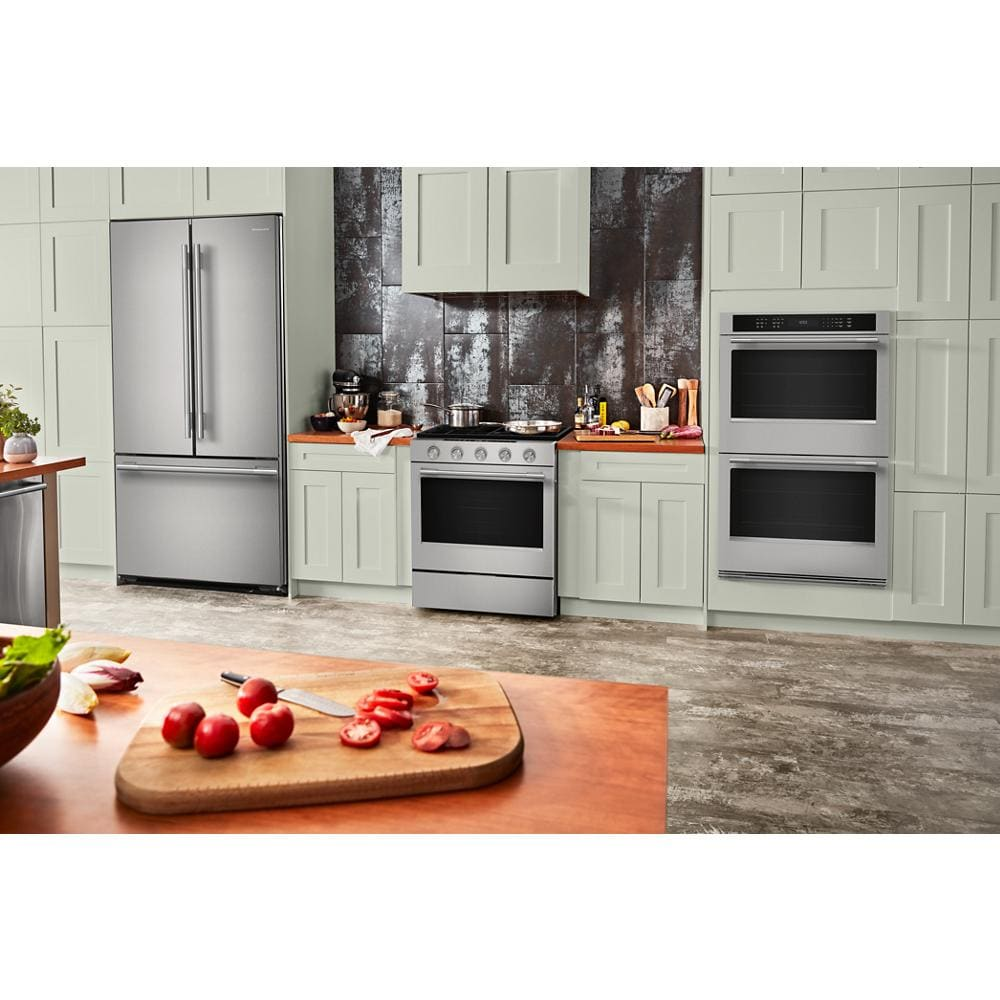Modern kitchen with stainless steel refrigerator, electric range, and built-in double wall oven in light green cabinetry.