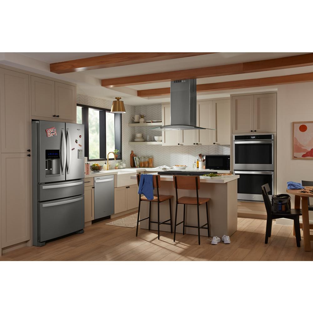 Contemporary kitchen with beige cabinetry, stainless steel appliances, and a curved glass island vent hood over breakfast bar seating.