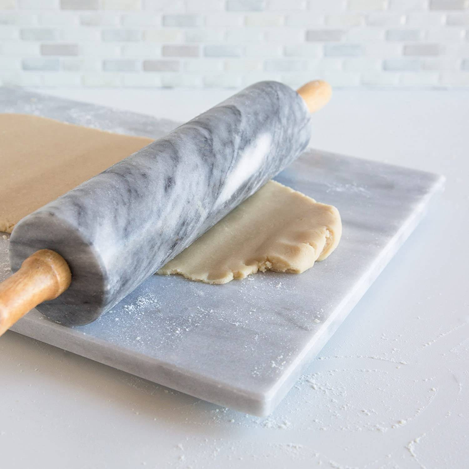 Gray marble rolling pin with wooden handles rolling dough on matching marble board in Kitchenware and Bakeware collections