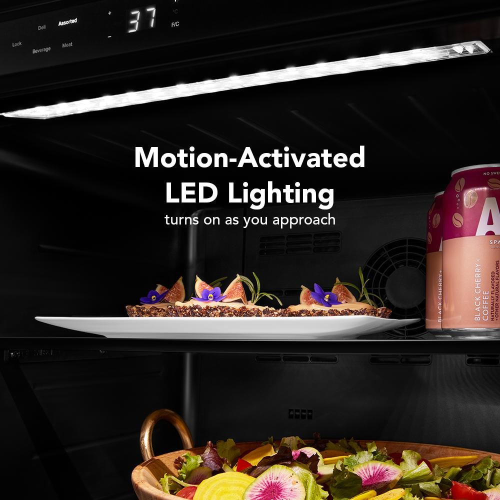 Interior view of undercounter refrigerator with motion-activated LED lighting illuminating food and beverages inside