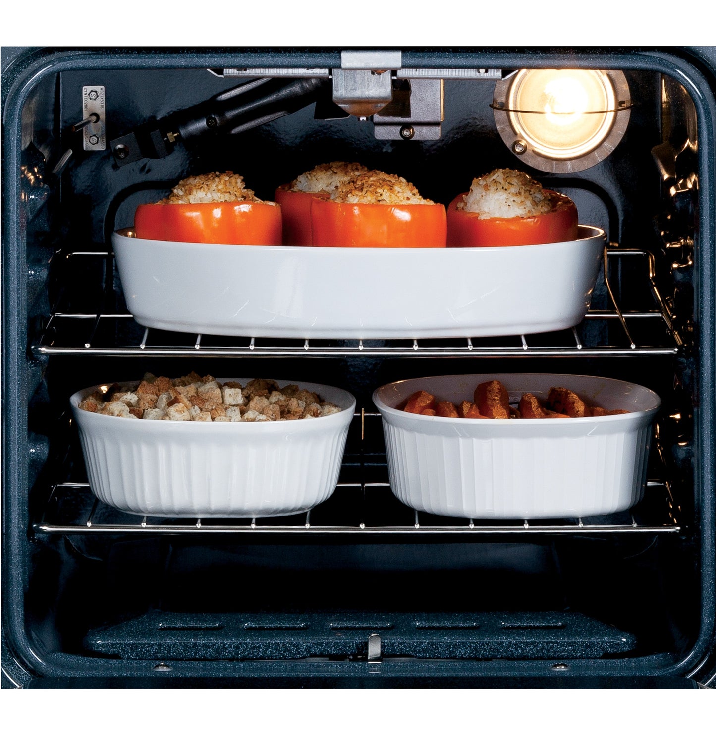Interior view of electric oven with three stuffed peppers and casserole dishes baking on two racks from Single Wall Ovens collection