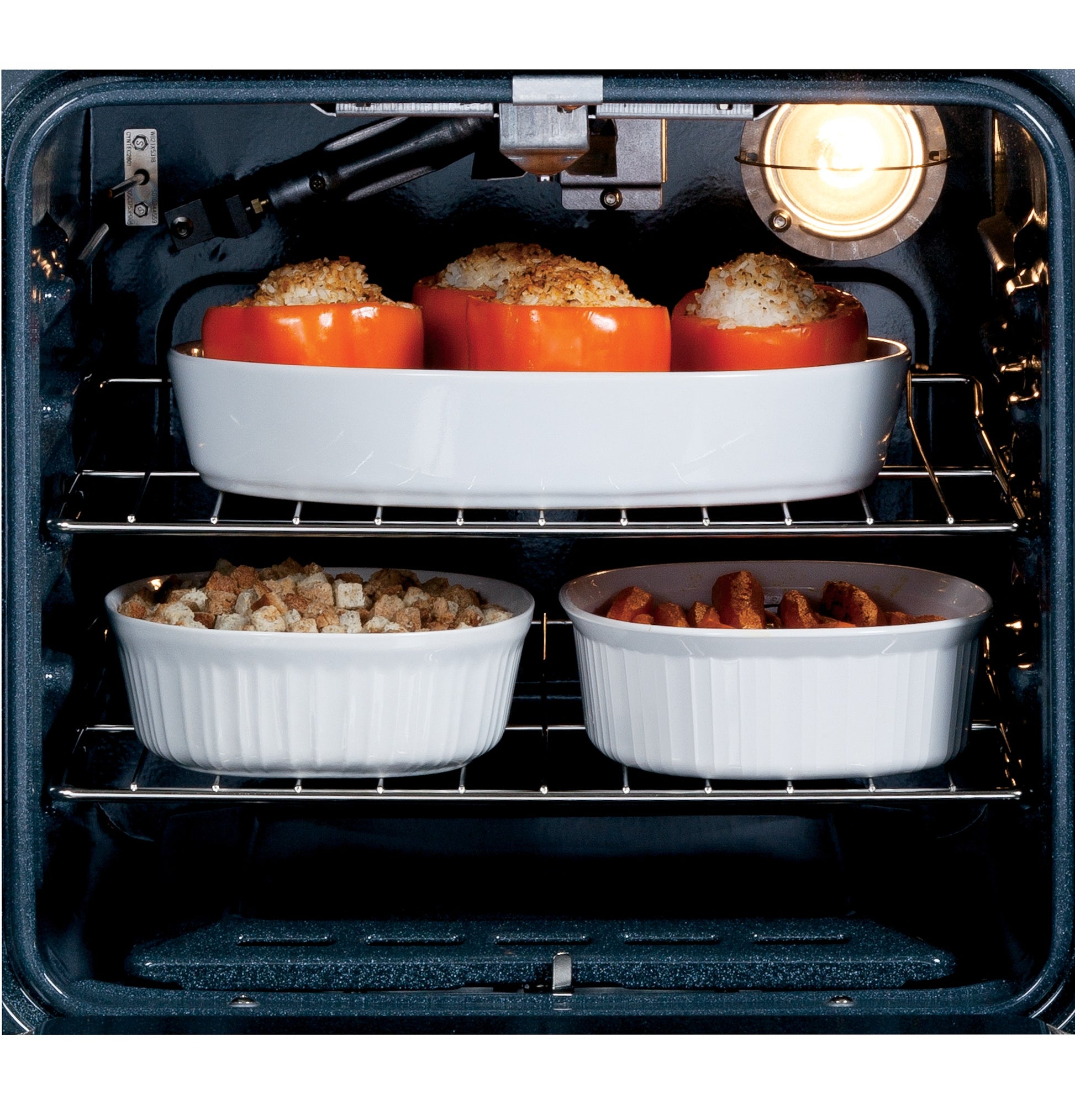 Interior view of electric oven with three stuffed peppers and casserole dishes baking on two racks from Single Wall Ovens collection