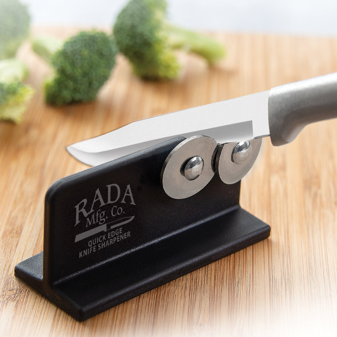 Black compact Rada knife sharpener with dual metal discs on wooden surface, part of kitchen utensils and gadgets under $50 collection
