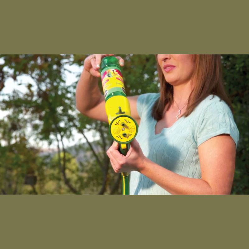 Woman holding a green and yellow liquid plant food refill for Miracle Gro feeder in lawn and garden plant care under $50