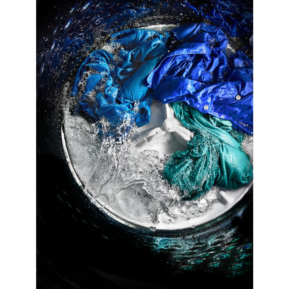 View inside a top load washer showing colorful clothes being washed among swirling water in washers & dryers collection