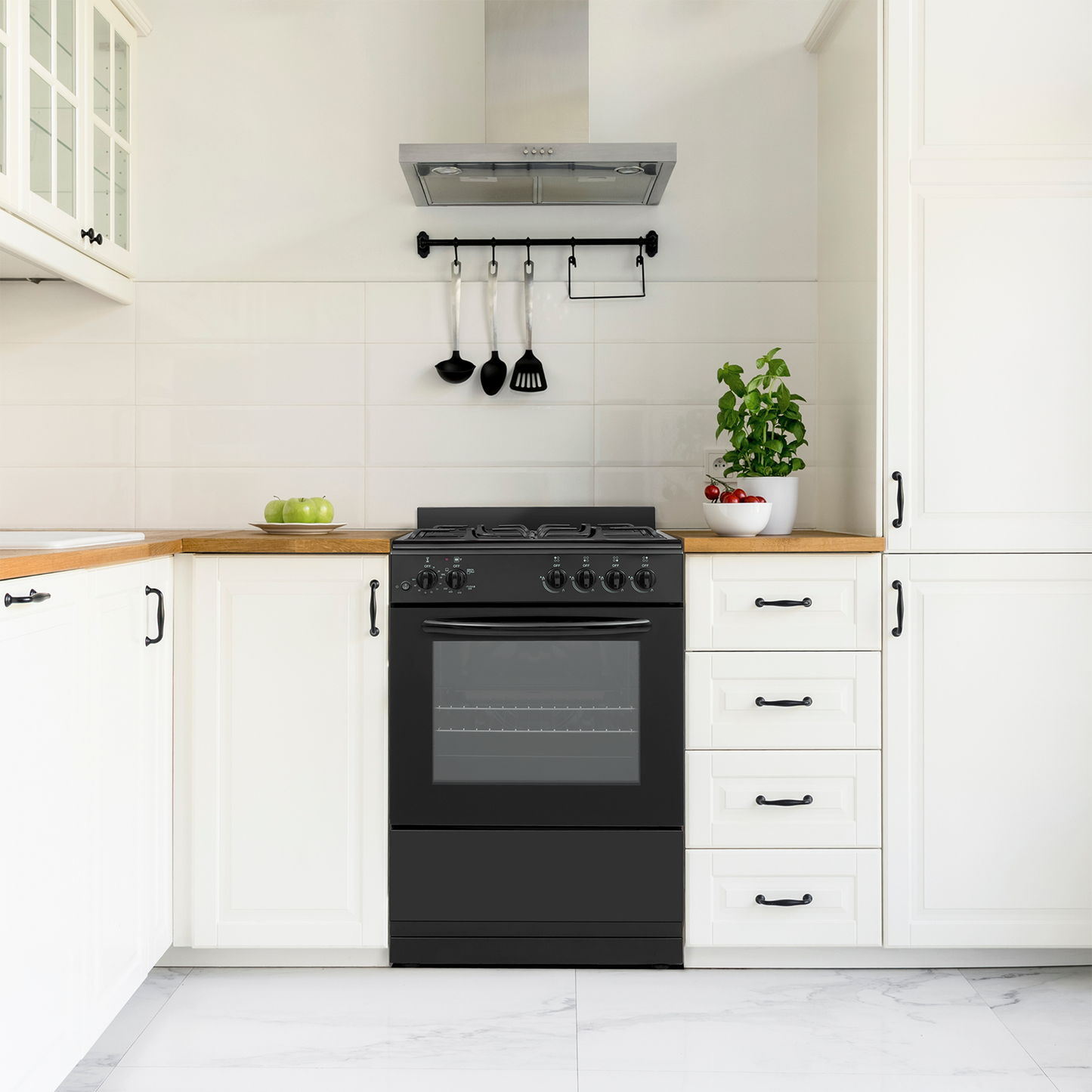 black 24-inch gas range with control knobs and glass oven door in bright white kitchen with wooden countertop and stainless steel hood