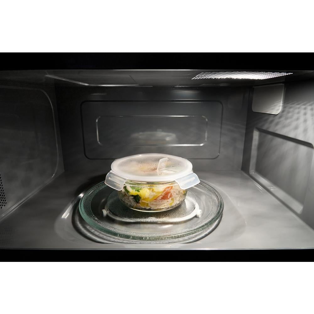Interior view of over the range microwave heating a covered bowl with mixed vegetables in kitchen appliances collection