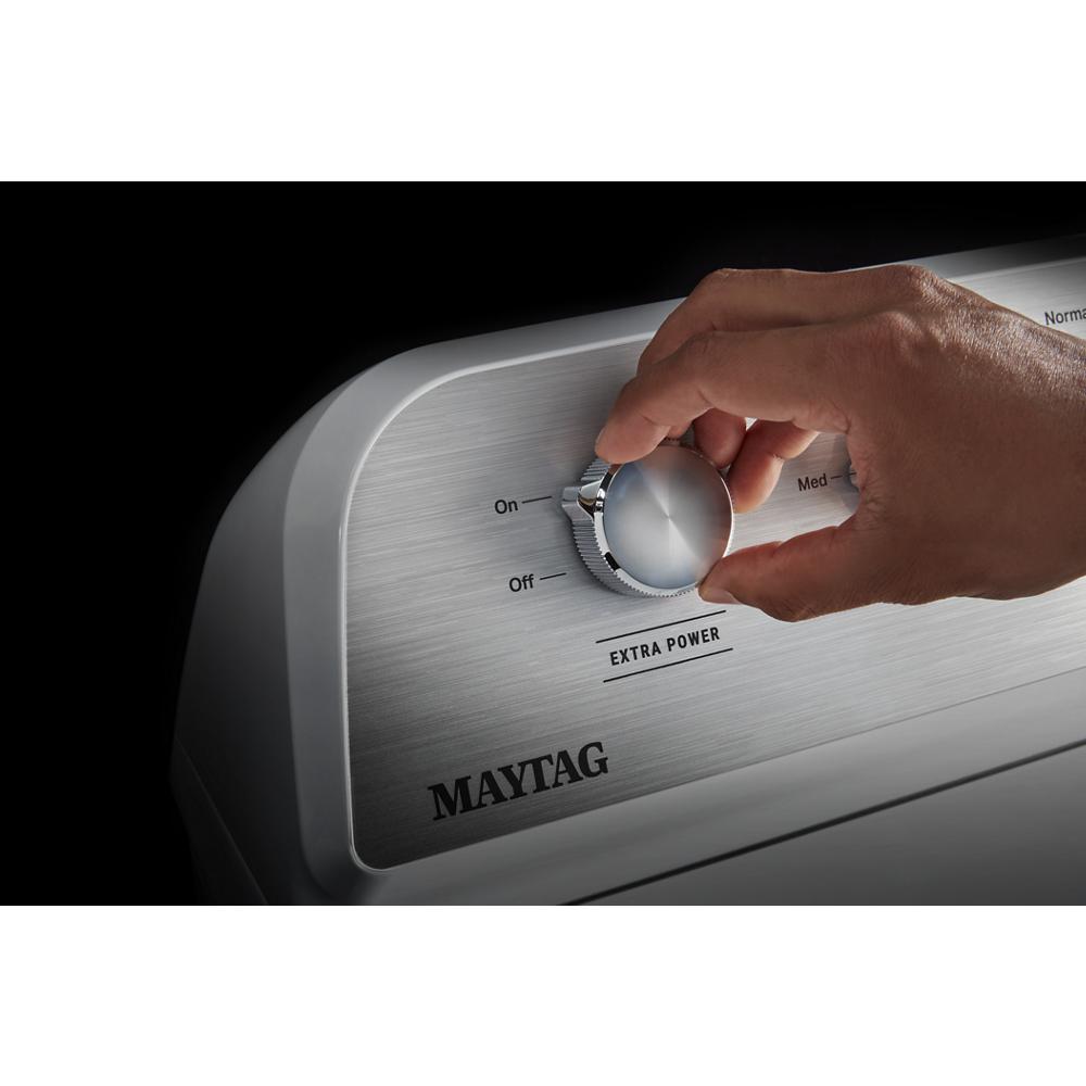 Hand adjusting silver control knob on brushed metal panel of a top load electric dryer in appliances collection