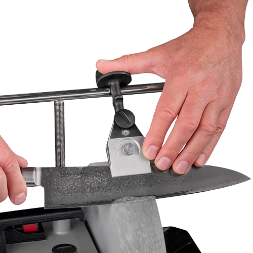 Hand operating centering knife jig with black knob to sharpen a kitchen knife blade on a grinding tool in home improvement
