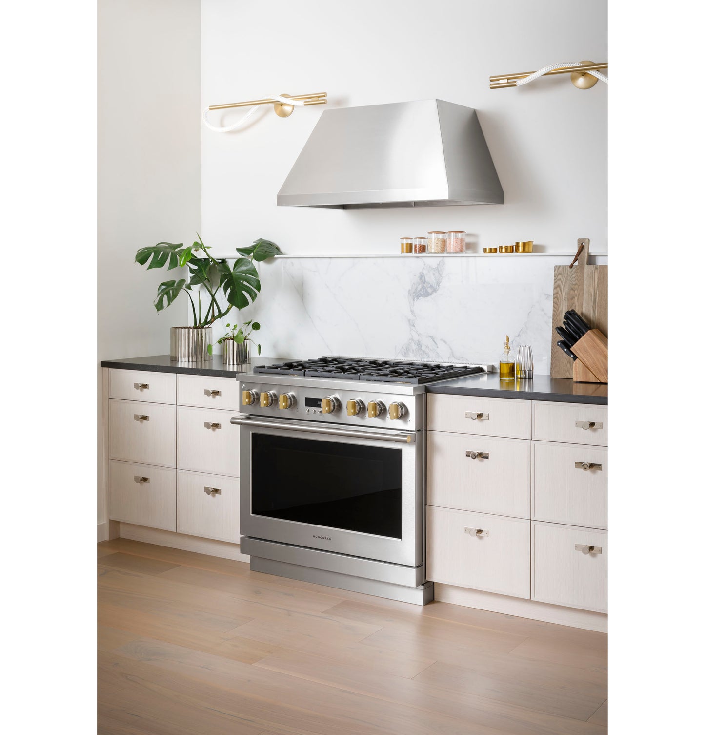 Stainless steel professional gas range with 4 burners and griddle set in modern kitchen with white cabinetry and marble backsplash