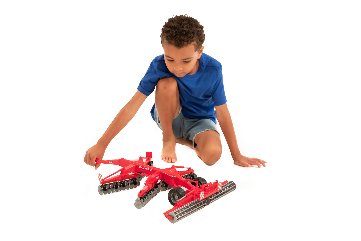 Child playing with red Bruder Kuhn Disc Harrow Discover XL toy featuring sturdy soil-cutting discs for imaginative farm play