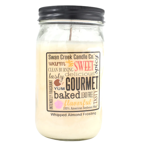 Glass jar candle with black lid featuring whipped almond frosting scent and decorative label with gourmet baking words