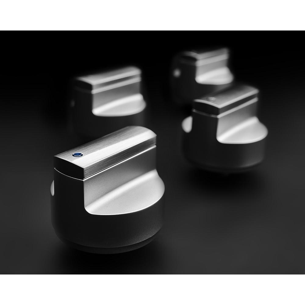 Set of four brushed stainless steel control knobs on black surface for gas cooktops in kitchen appliances category