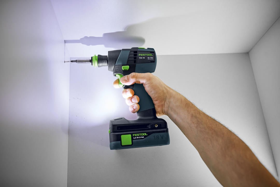 Hand holding compact Festool cordless drill driving screws into white cabinet for home improvement tasks