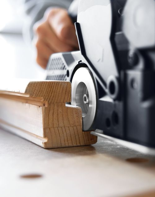 Close-up of a power planer smoothing a grooved wooden board for tools and home improvement projects