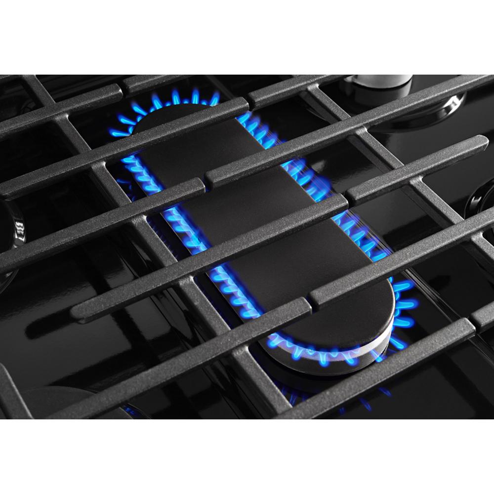 Close-up of blue burner flames and edge to edge cast-iron grates on freestanding gas range for kitchen appliances collections